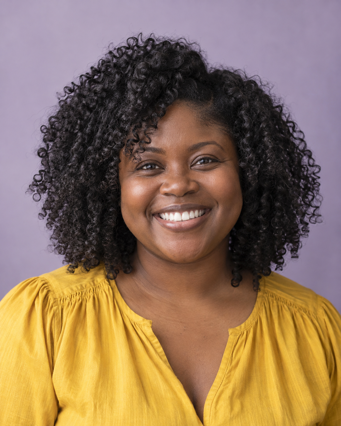 Medium-length defined black curls framing a smiling adult’s face